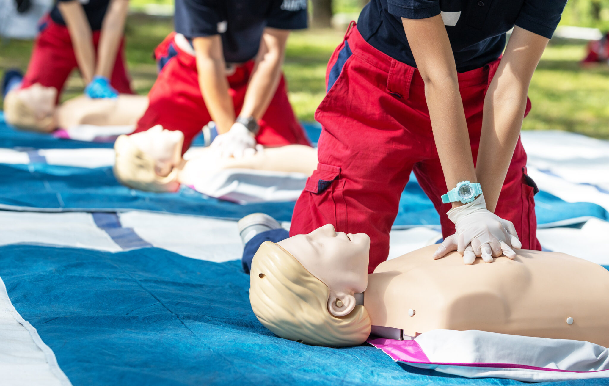 CPR training with mannequins on blue mats.