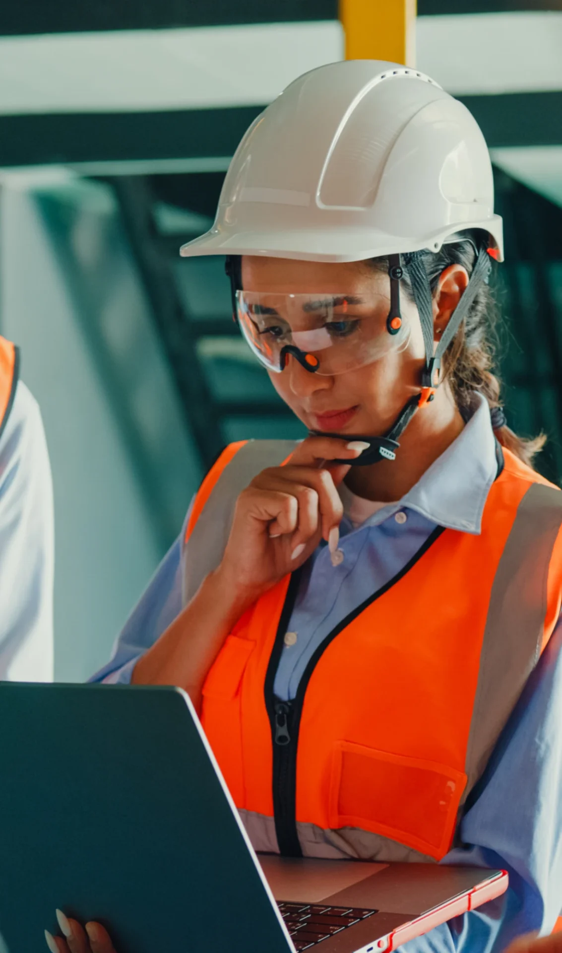 Engineer in safety gear using laptop.