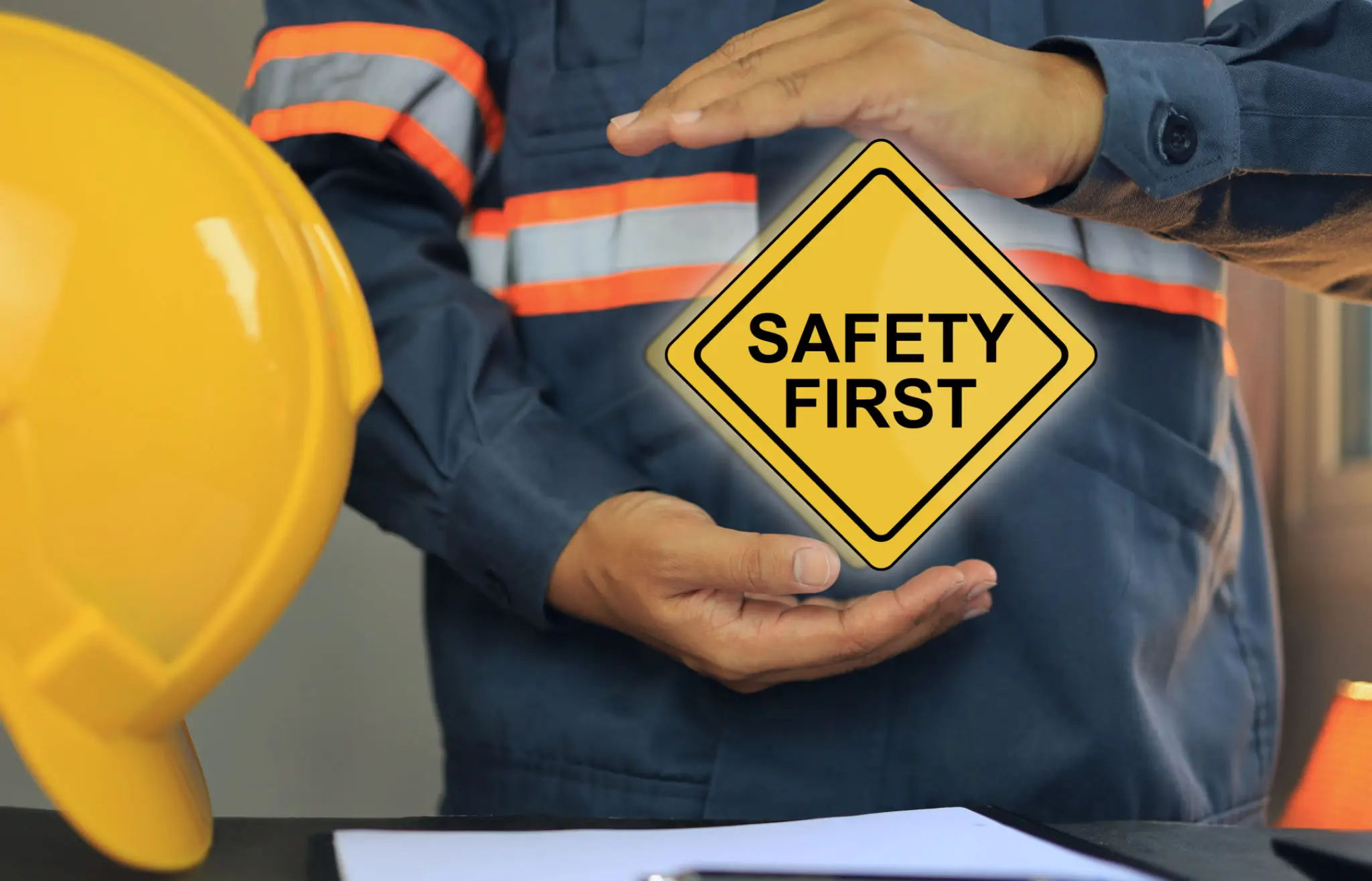 Worker holding a 'Safety First' sign emphasizing workplace safety.