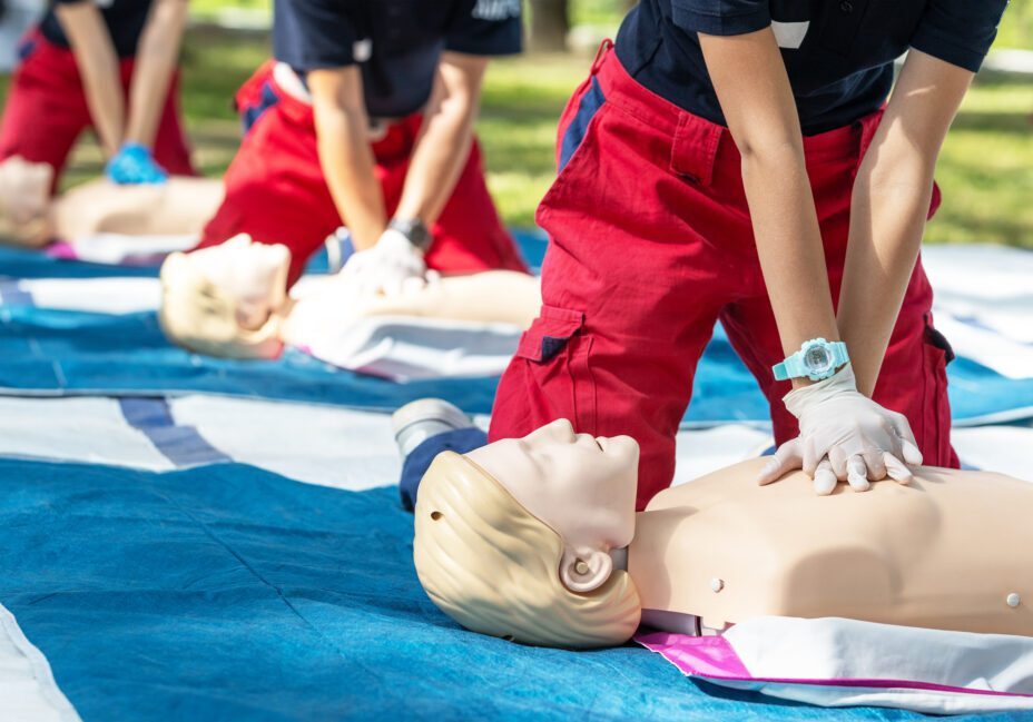 CPR training with mannequins on blue mats.